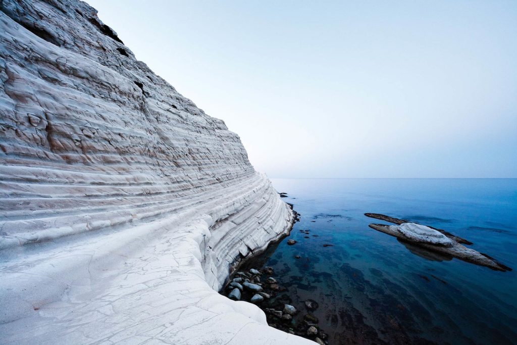 fotografia di paesaggio, mare, terra, scogli bianchi e cielo blu