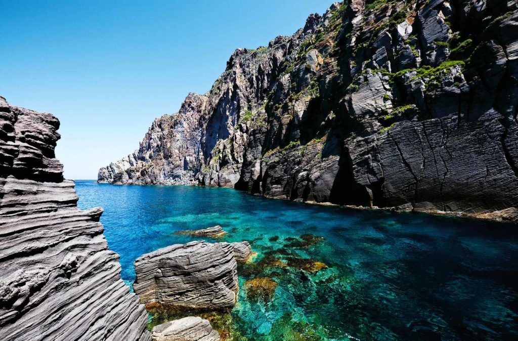 fotografia di paesaggio, mare, terra, scogli e cielo blu