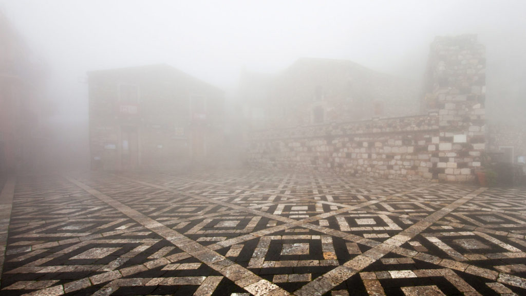 borgo di Castelmola. La nebbia cala sulla piazza e su tutto il borgo fino alla vicina città di Taormina nella Sicilia orientale